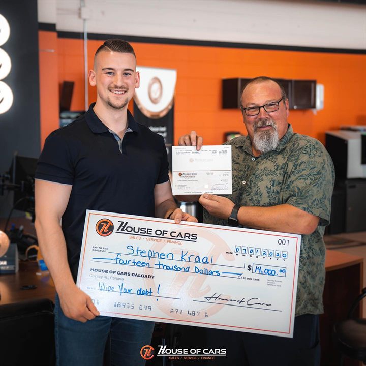 A 2020 Wipe Out Your Debt winner and a House of Cars staff member holding an oversized cheque for fourteen thousand dollars.