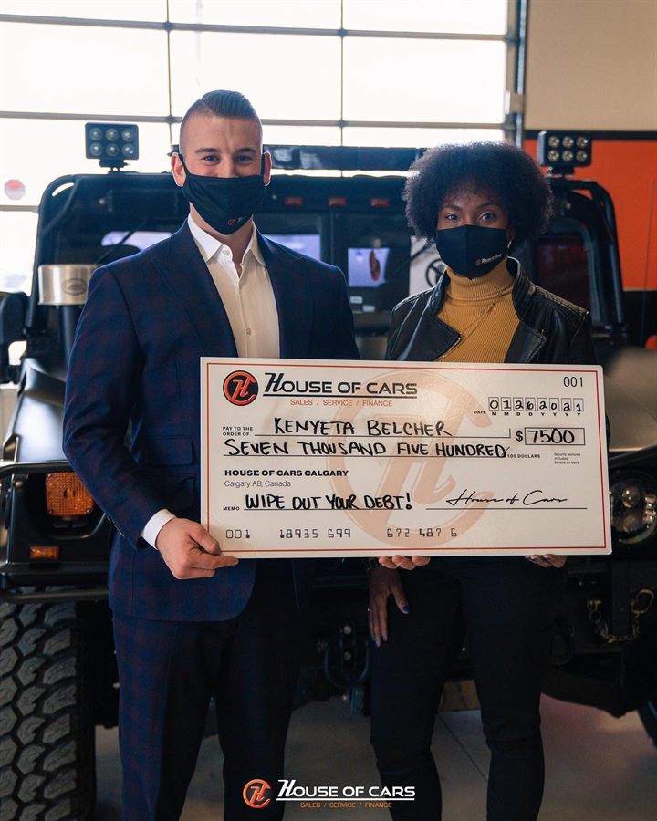 A 2021 Wipe Out Your Debt winner holding an oversized House of Cars cheque for seven thousand five hundred dollars.