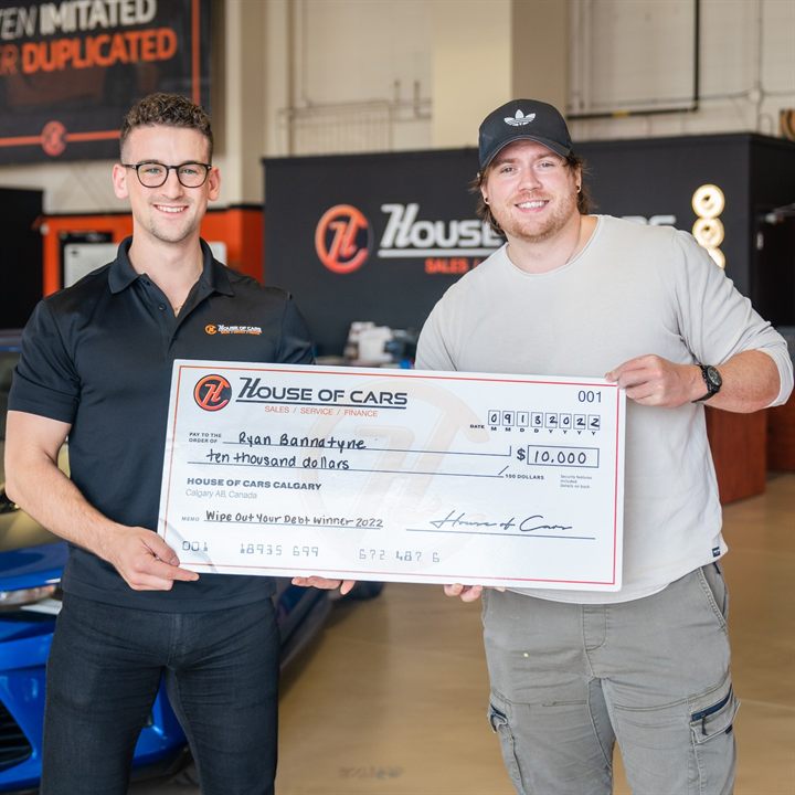 A 2022 Wipe Out Your Debt winner holding an oversized House of Cars cheque for ten thousand dollars.