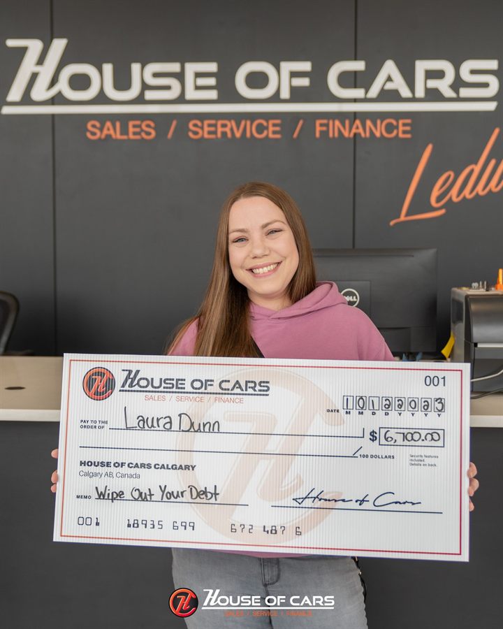 A 2023 Wipe Out Your Debt winner holding an oversized House of Cars cheque for six thousand seven hundred dollars.