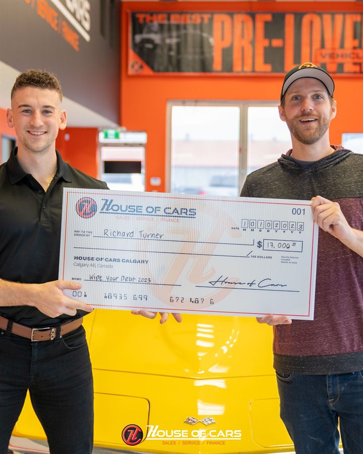 A 2023 Wipe Out Your Debt winner and a House of Cars staff member holding an oversized cheque for seventeen thousand dollars.